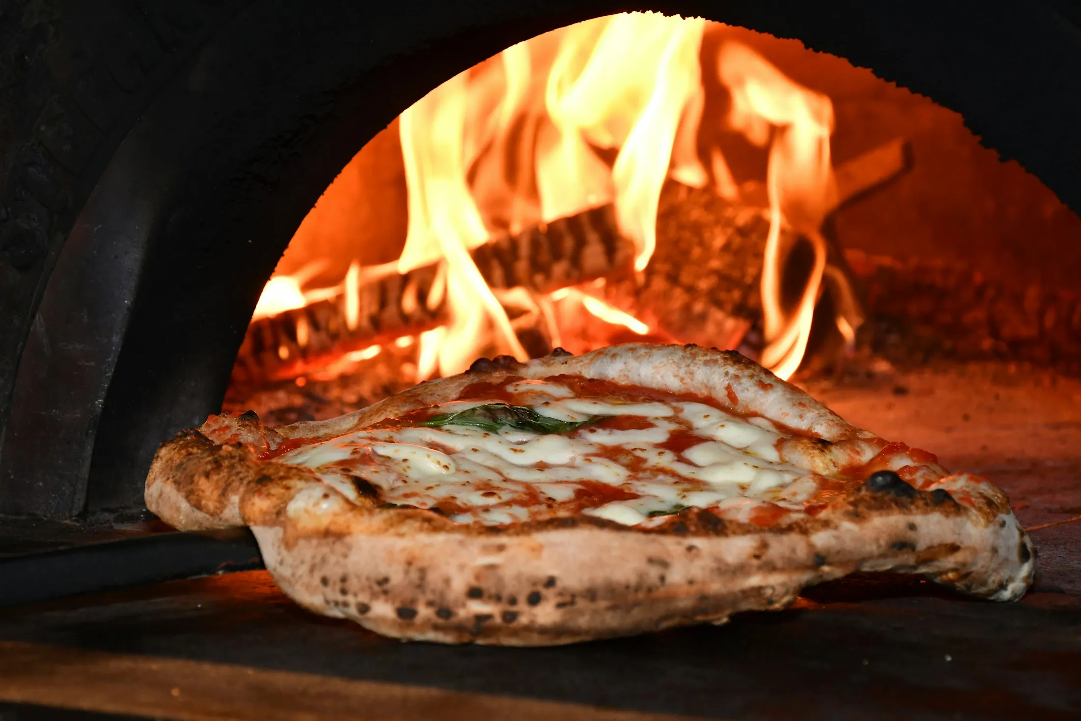 Une pizza enfournée près des flammes