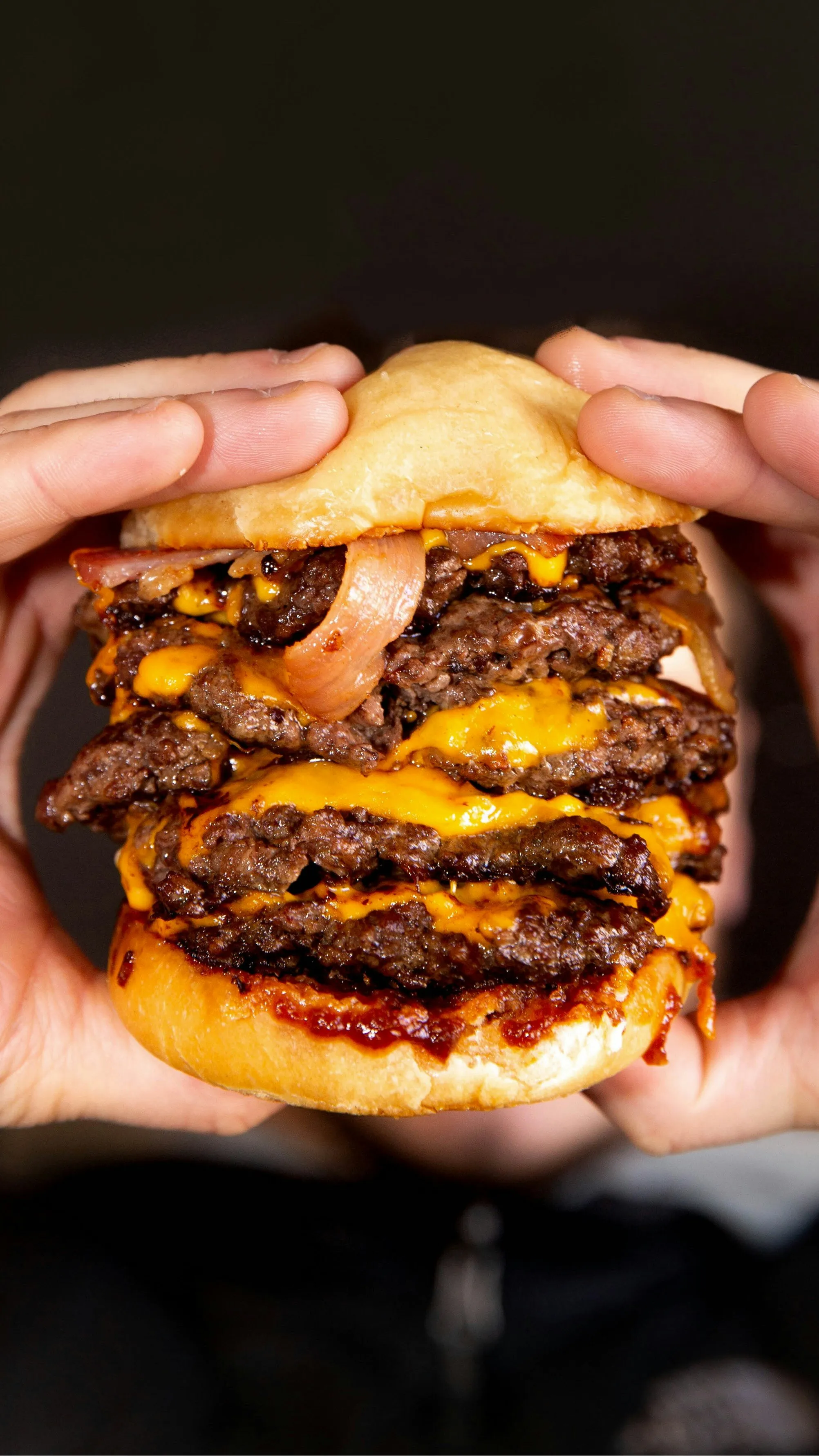 Deux mains tiennent un burger à quatre steaks